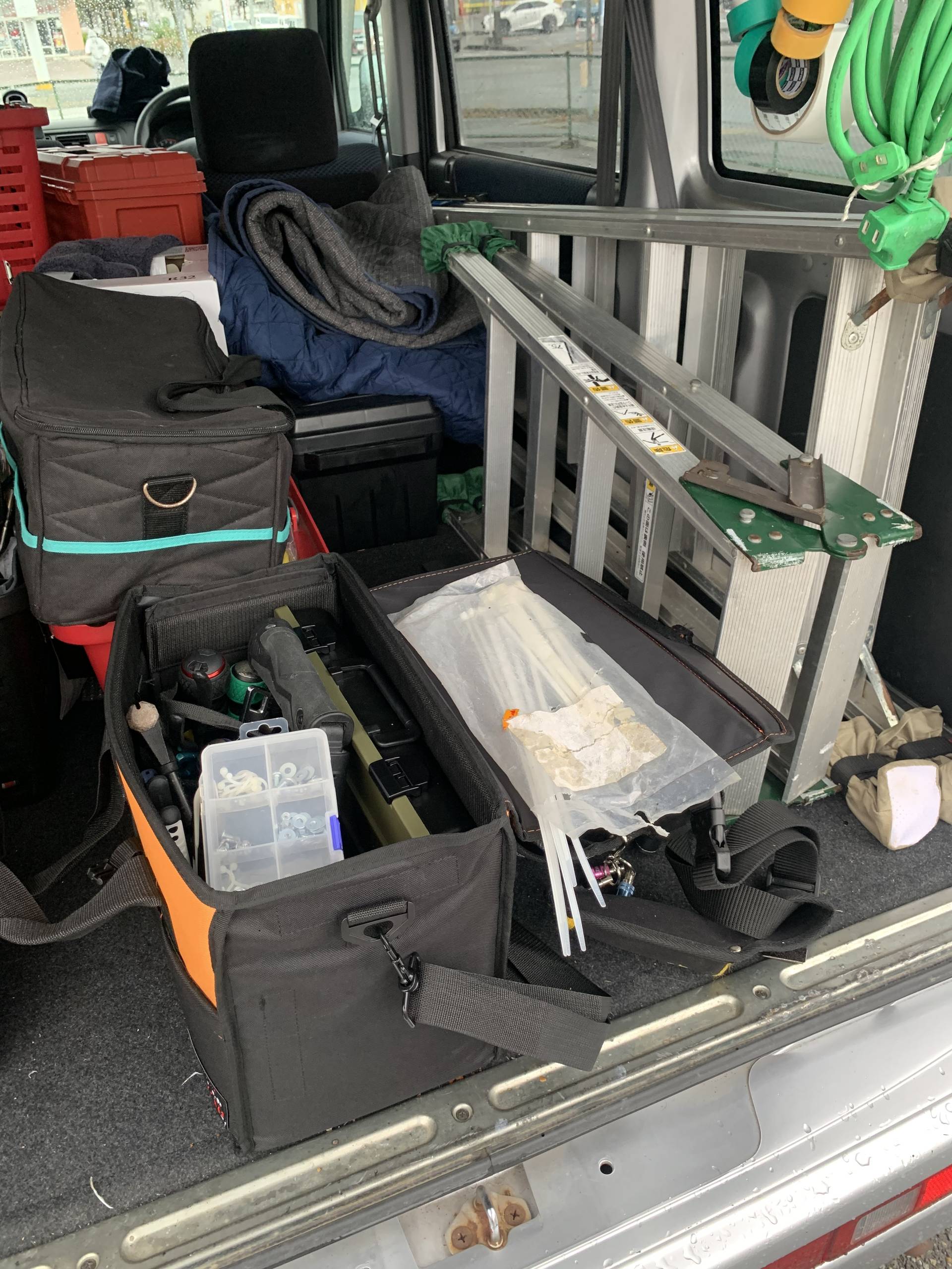 作業車の荷室に整理して積まれた脚立や工具ケース
