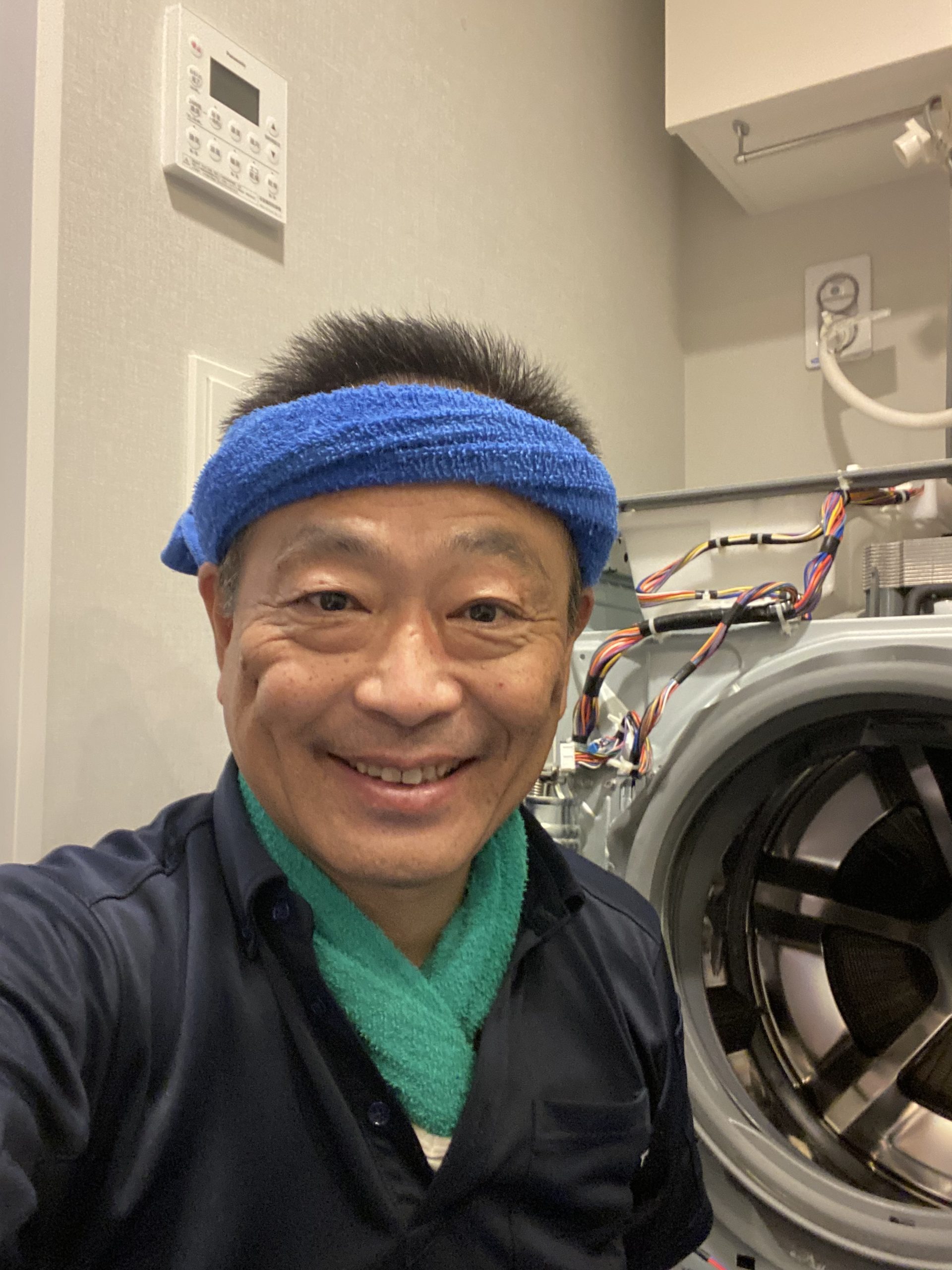 洗濯機の修理現場で笑顔を見せる猪俣さん