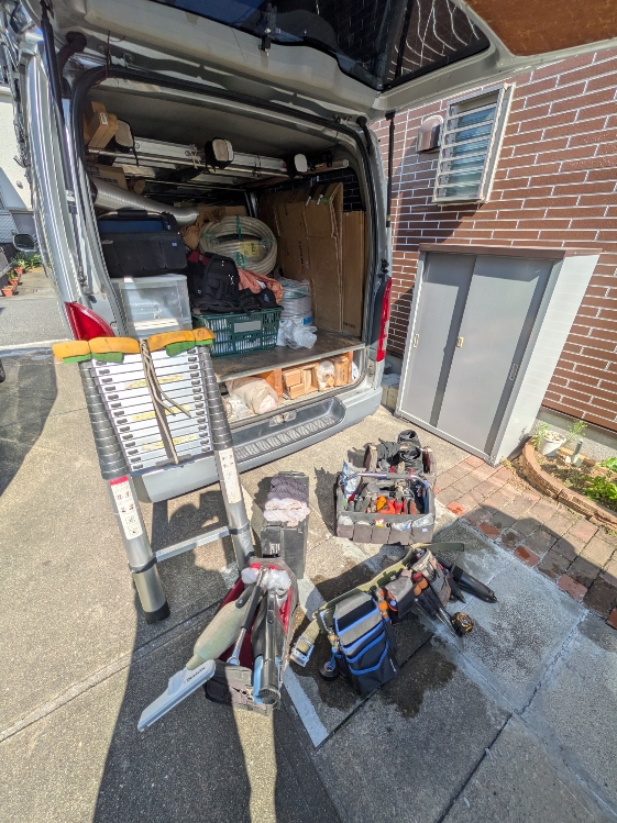 荷室を開けた工事車両の後方に、工具箱や電動工具、資材を並べた様子。