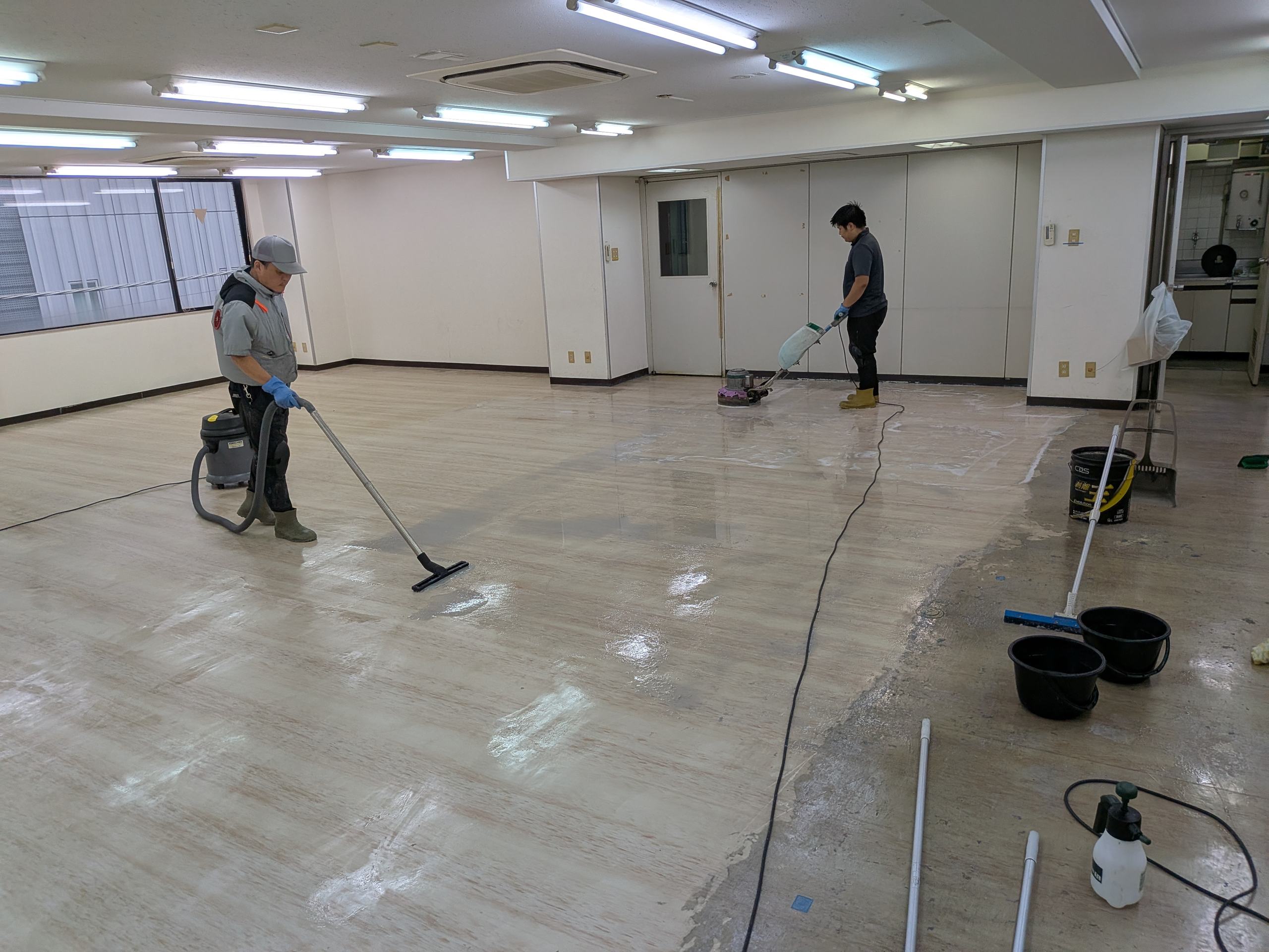 オフィスフロアの床を清掃するスタッフ
